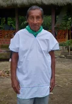 Retrato de un mayor con cusma blanca y pañuelo verde frente al tambo (línea de tiempo).