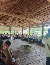 Asamblea dentro del tambo alrededor de la tulpa, con muchas personas sentadas (línea de tiempo).