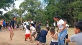 Niños y adultos jugando al aire libre a halar la cuerda (línea de tiempo).