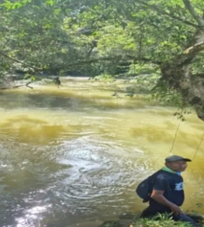 Hombre pescando a la orilla de un río de aguas turbias (fuentes hídricas).