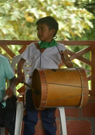 Niño con cusma blanca y pañuelo verde tocando un bombo (Atun Puncha).