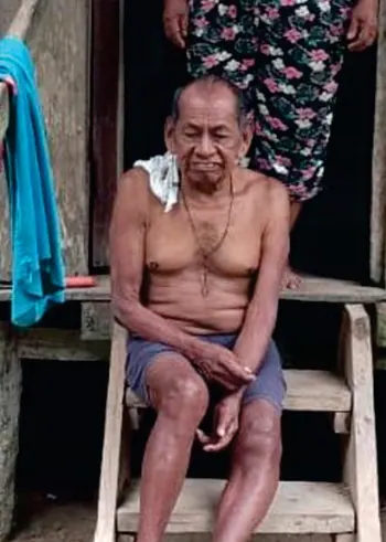 Retrato del mayor Celimo Jojoa Jojoa sentado en la entrada de una casa de madera (Adultos mayores).
