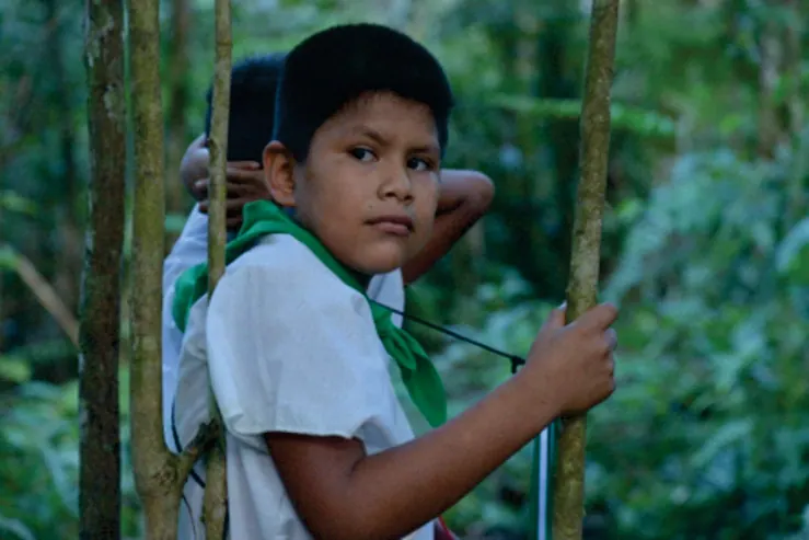 Niño con cusma blanca y pañuelo verde sosteniendo un palo en la selva (Niños y niñas).