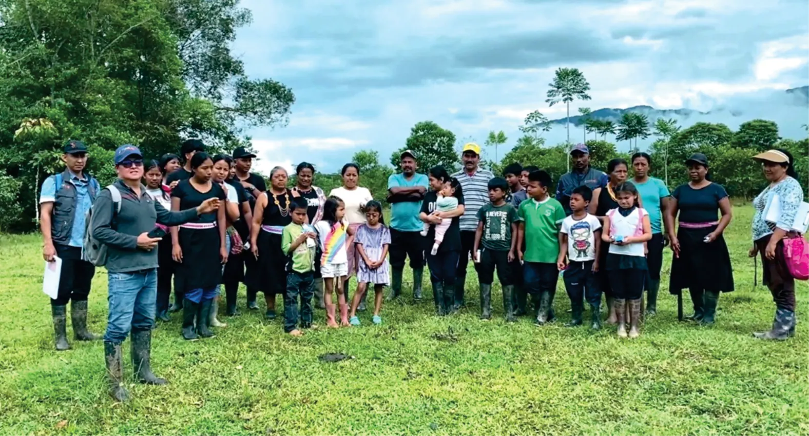 Grupo numeroso de la comunidad, con niños y jóvenes, reunido en un potrero.