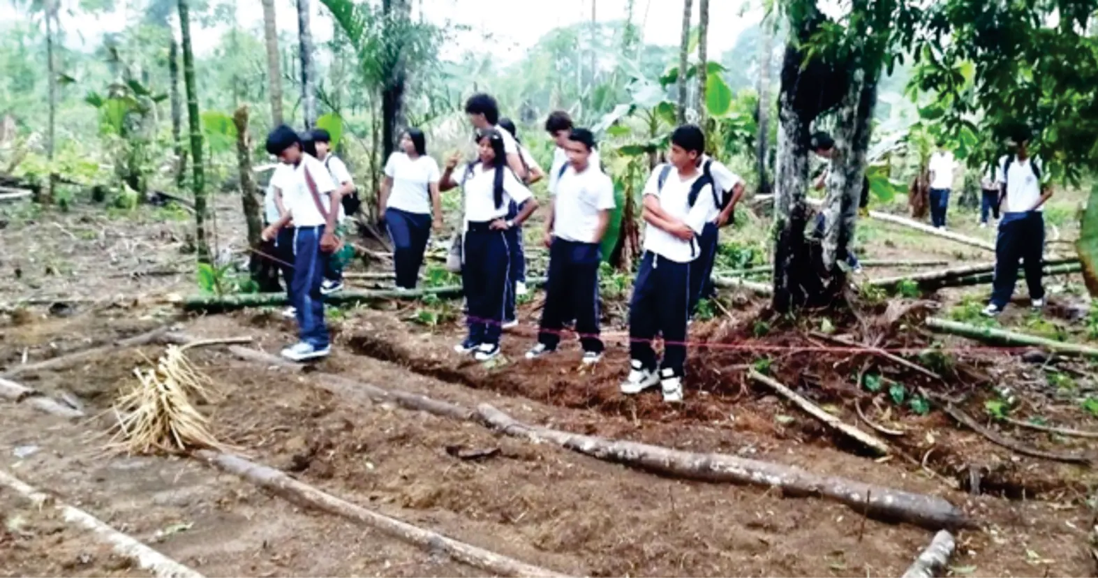 Grupo de jóvenes con uniforme en un terreno preparado para la siembra.