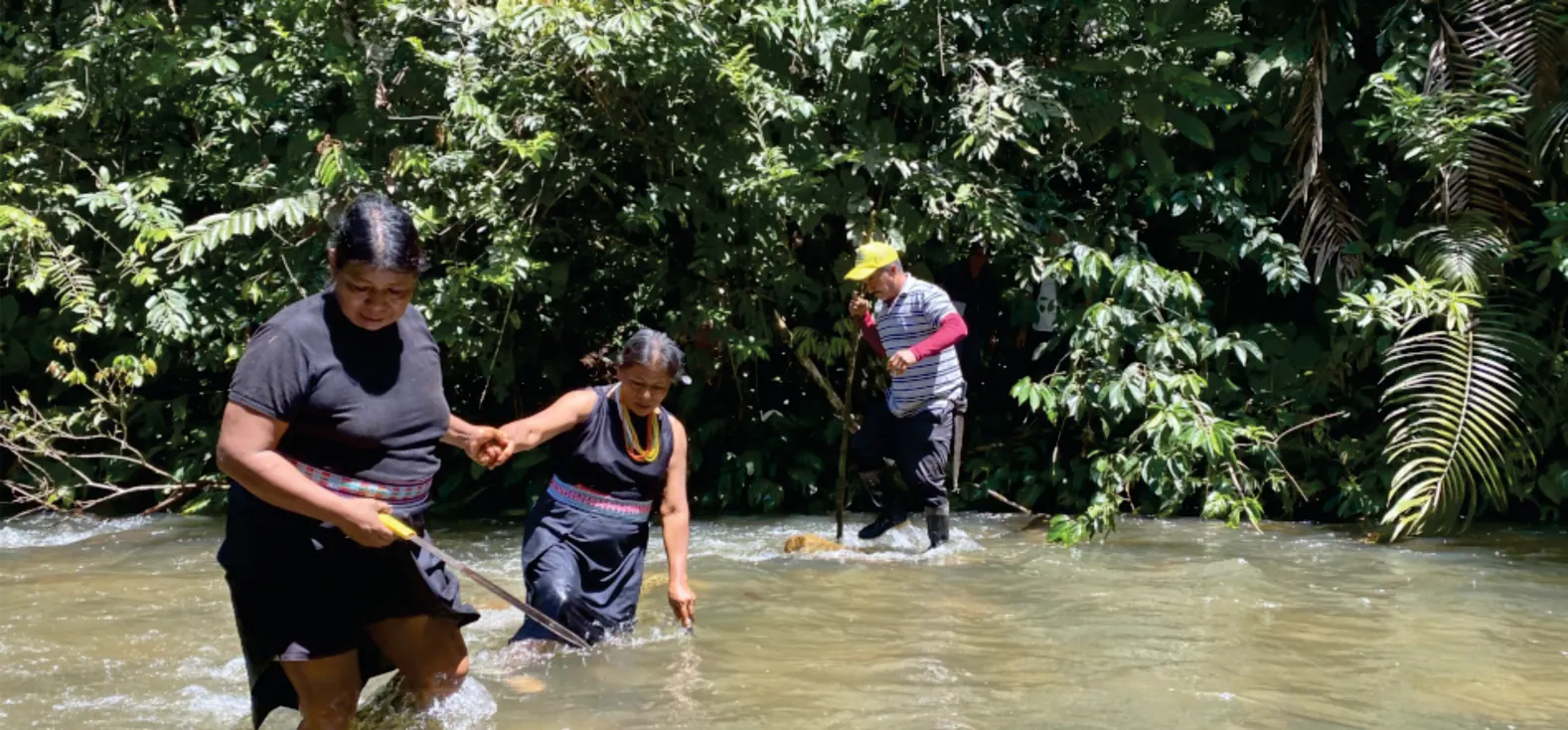 Personas que cruzan un río tomadas de la mano.