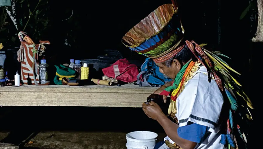 Taita con corona de plumas preparando una ceremonia (registro fotográfico).