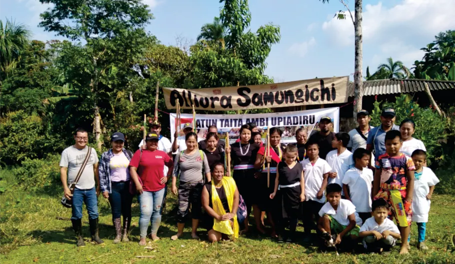 Foto grupal de la comunidad frente a una pancarta con el nombre «Atun Taita Ambi Upiadiru» (registro fotográfico).