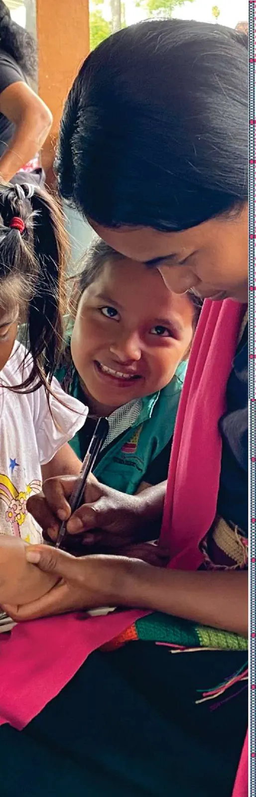 Niña sonriente junto a una mujer con blusa negra y chal rosado, en primer plano.