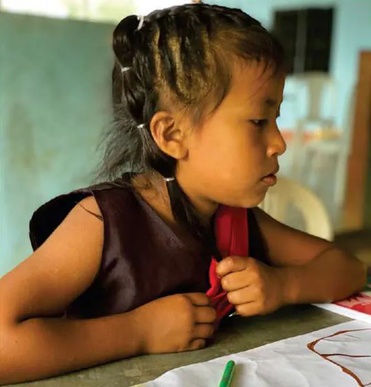 Niña con trenzas que dibuja sobre un papelógrafo.