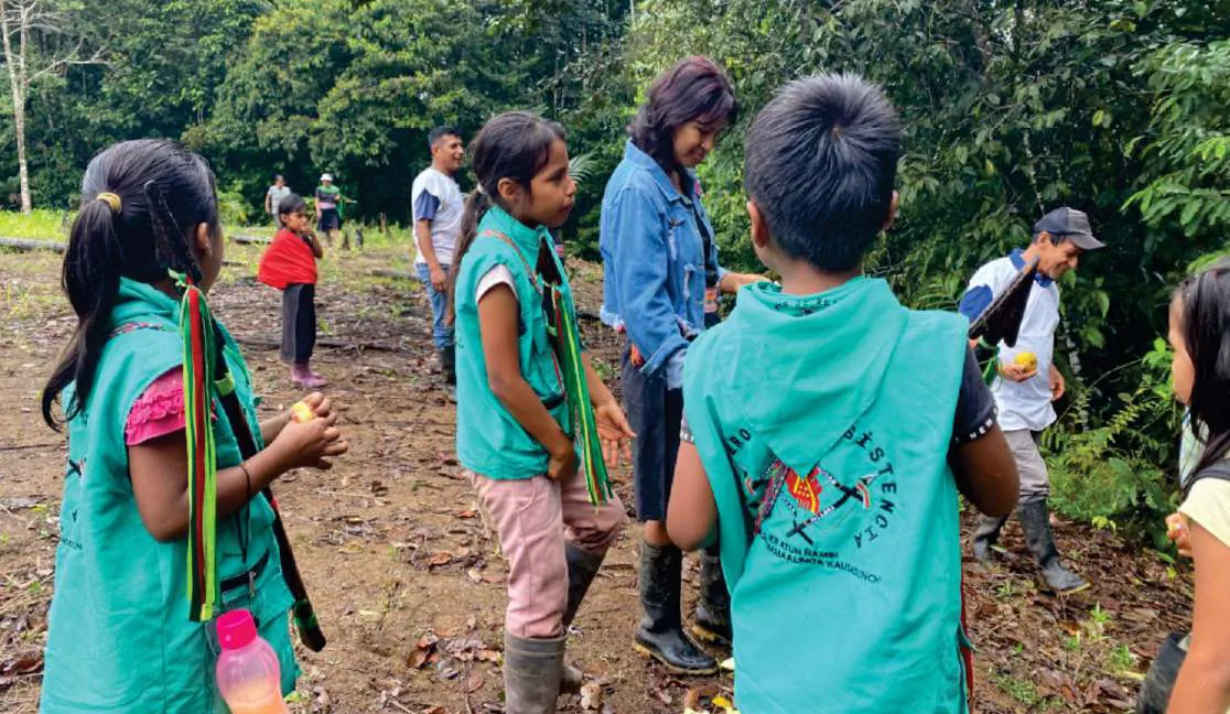 Niños con chaleco de la guardia y adultos en la chagra.
