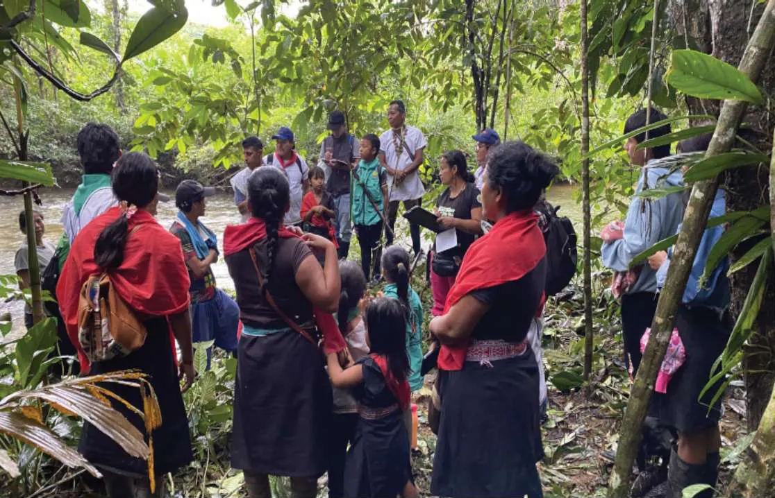 Mujeres con chal rojo y niños en el bosque, en un recorrido.