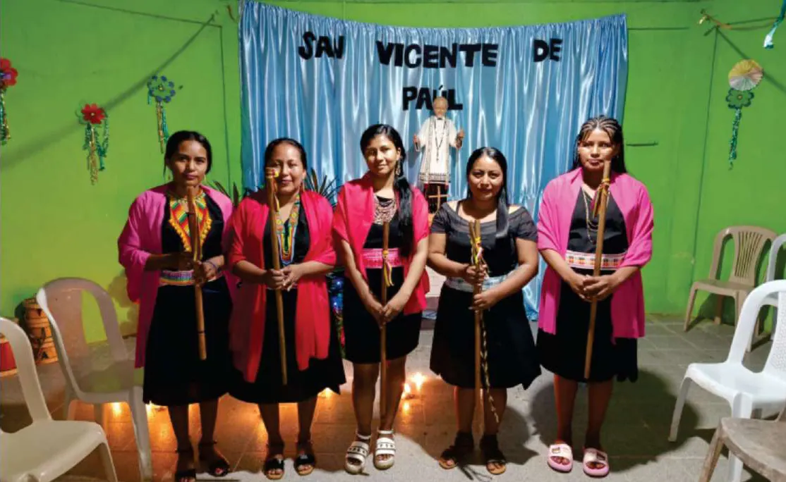 Cinco mujeres con traje propio y bastones de mando frente al altar de San Vicente de Paúl.