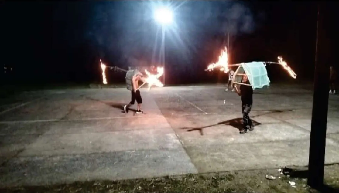Juego tradicional nocturno con fuego en una cancha.