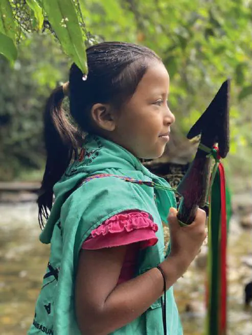 Niña con chaleco de la guardia y lanza, junto a un río.