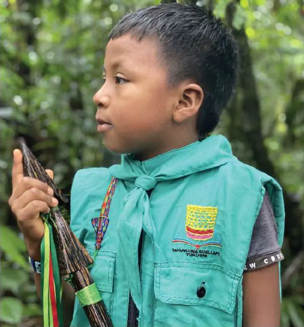 Niño con chaleco y pañoleta de la guardia indígena y lanza.
