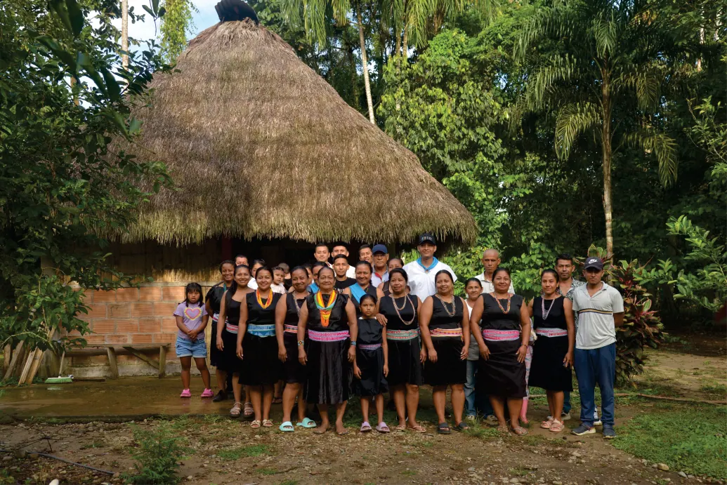 Foto grupal de la comunidad frente al tambo de techo de paja.