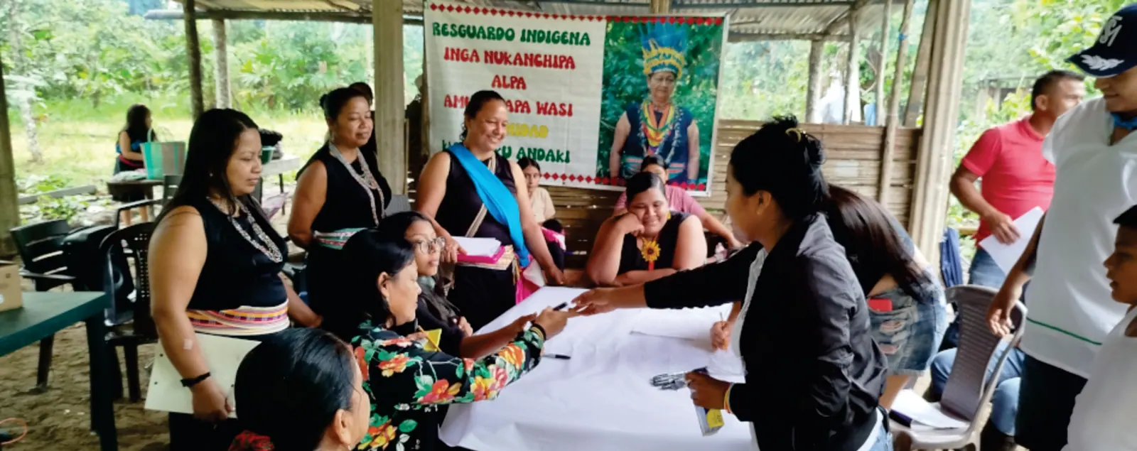 Mujeres trabajando alrededor de una mesa, con la pancarta del resguardo al fondo.