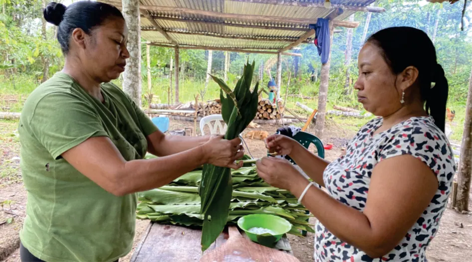 Dos mujeres que envuelven alimentos en hojas (registro fotográfico).