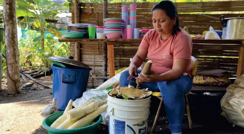 Mujer sentada que prepara alimentos en una cocina (registro fotográfico).