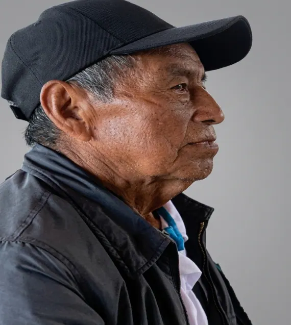 Retrato de perfil de un mayor con gorra negra y chaqueta oscura.