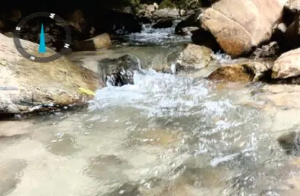 Corriente de quebrada entre rocas, con marca de geolocalización.