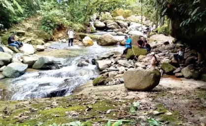 Quebrada con piedras grandes y personas al fondo.