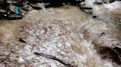 Corriente de agua sobre lecho rocoso, con marca de geolocalización.