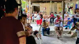 Reunión dentro de un tambo con personas sentadas en bancas.
