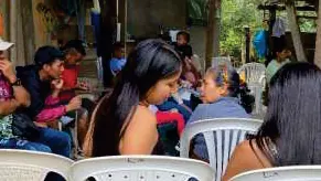 Jóvenes y mujeres sentados en sillas plásticas durante un taller.