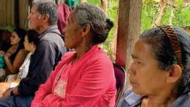 Mujeres mayores sentadas escuchando en una reunión.