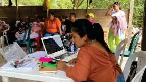 Mujer trabajando en un computador portátil durante un taller; personas sentadas alrededor.