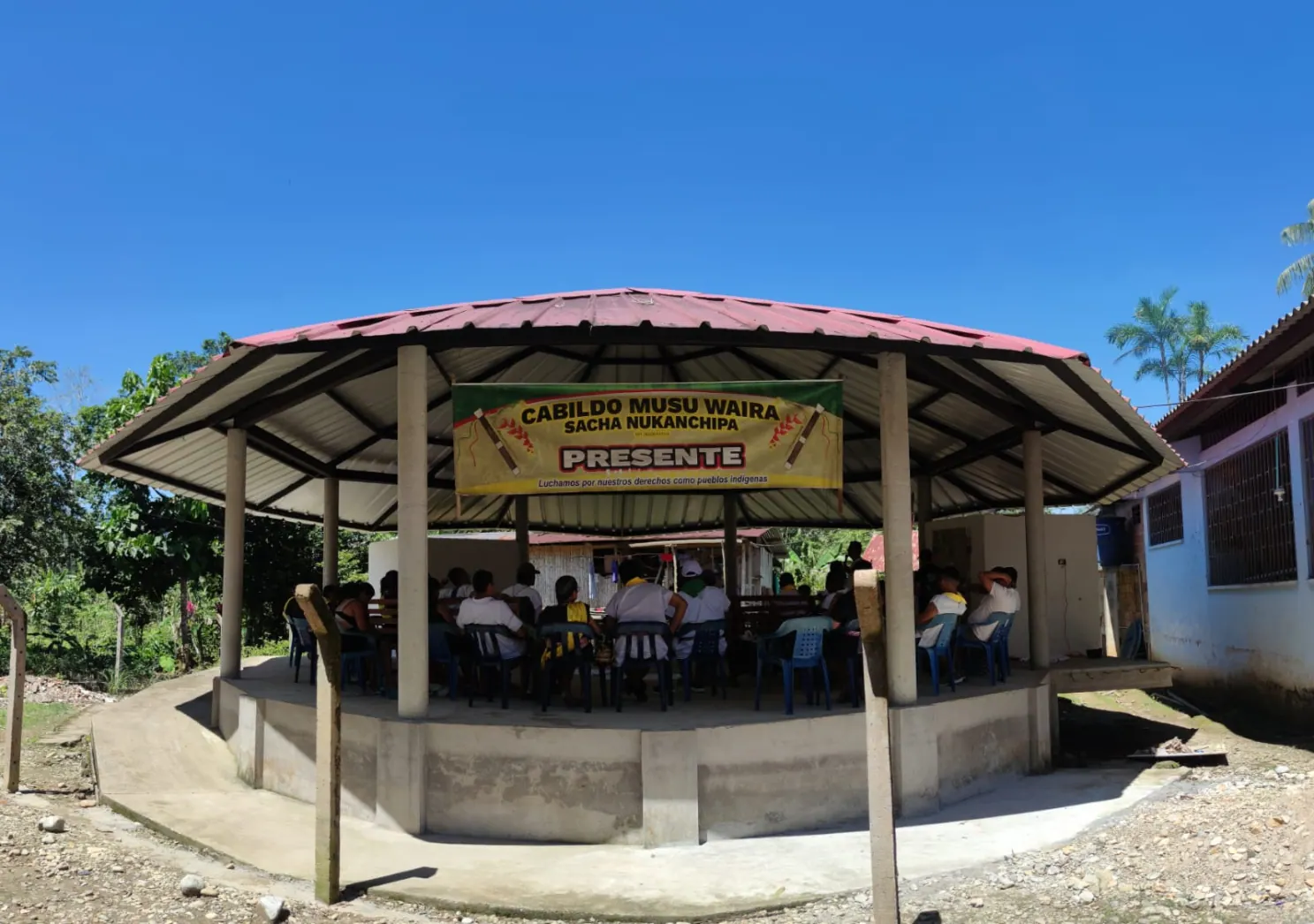 Kiosco comunitario con aviso «Cabildo Musu Waira … Presente» y personas reunidas adentro.