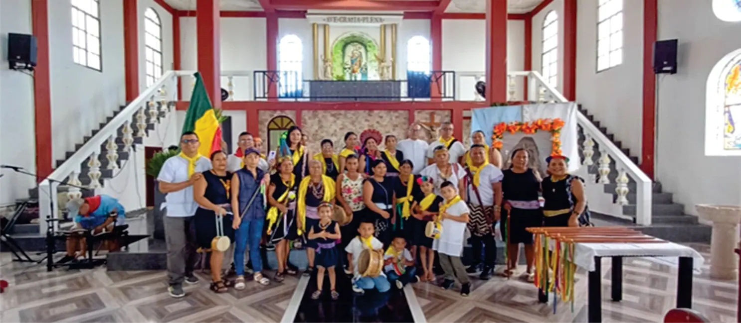 Grupo de personas posando en un salón con escaleras y banderas.