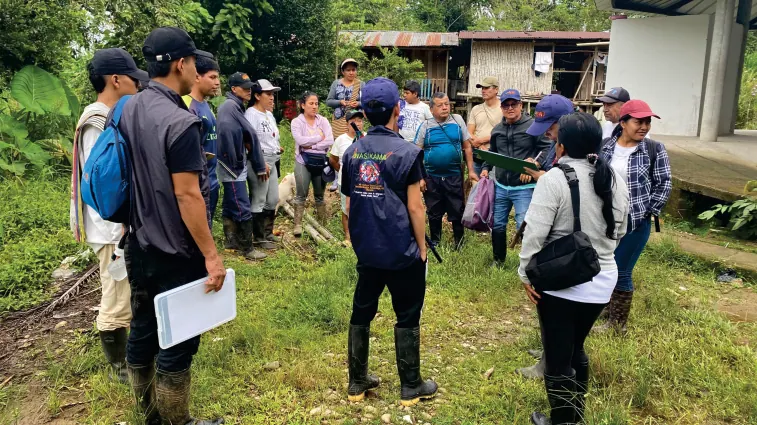 Grupo de personas con chalecos en un potrero durante un recorrido.