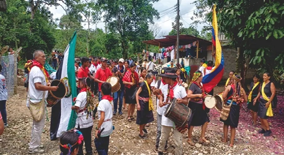 Desfile con banderas, tambores y personas con traje tradicional.