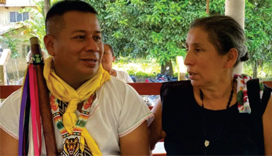 Hombre con pañoleta amarilla y mujer mayor conversando.