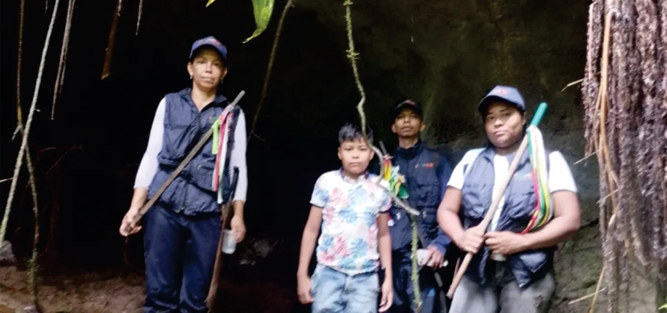 Wasikamas con bastones y una niña en un sitio oscuro del bosque.