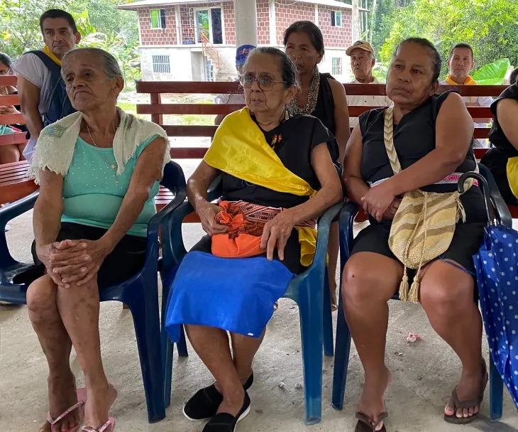 Mujeres mayores sentadas en sillas plásticas.