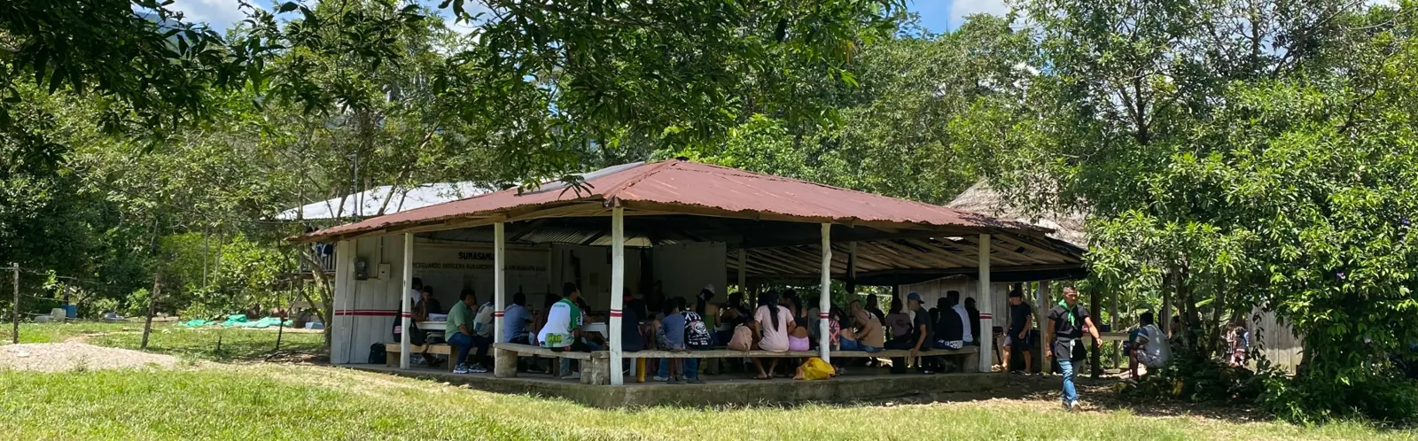 Tambo comunitario en un campo con personas reunidas.