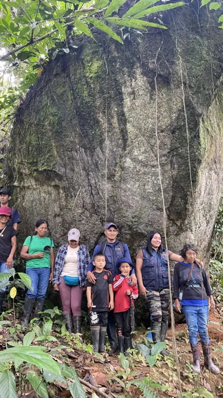 Grupo de personas al pie de una roca grande en el bosque.