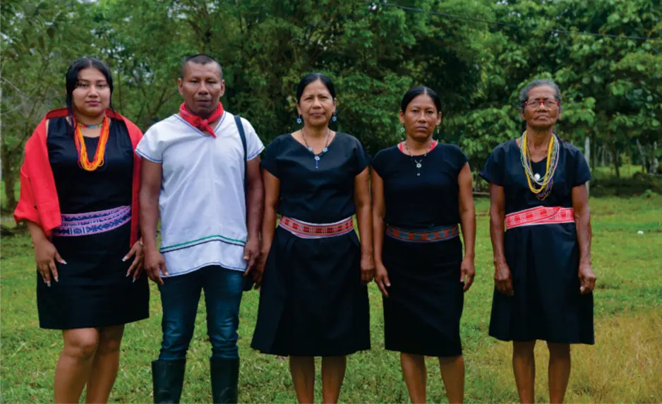 Cinco personas con traje tradicional de pie en un campo.