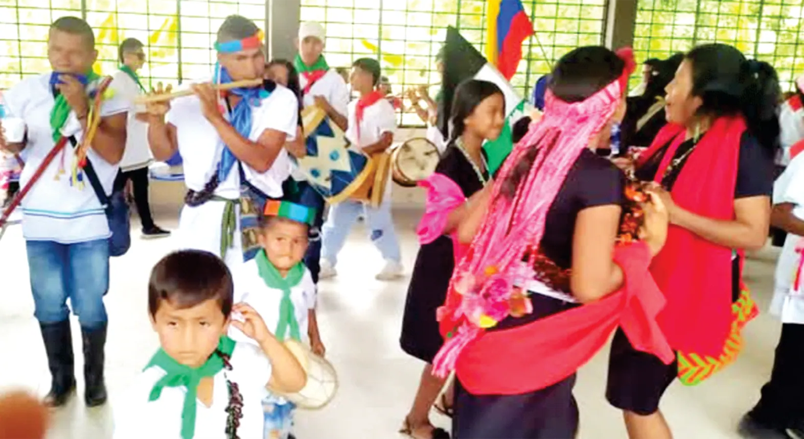 Danza con flautas, niños y mujeres con traje tradicional.