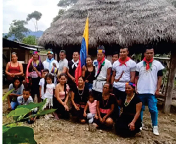Grupo de la comunidad frente a un tambo con bandera de Colombia.