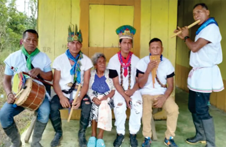 Músicos con coronas y traje blanco sentados con tambor y flautas.
