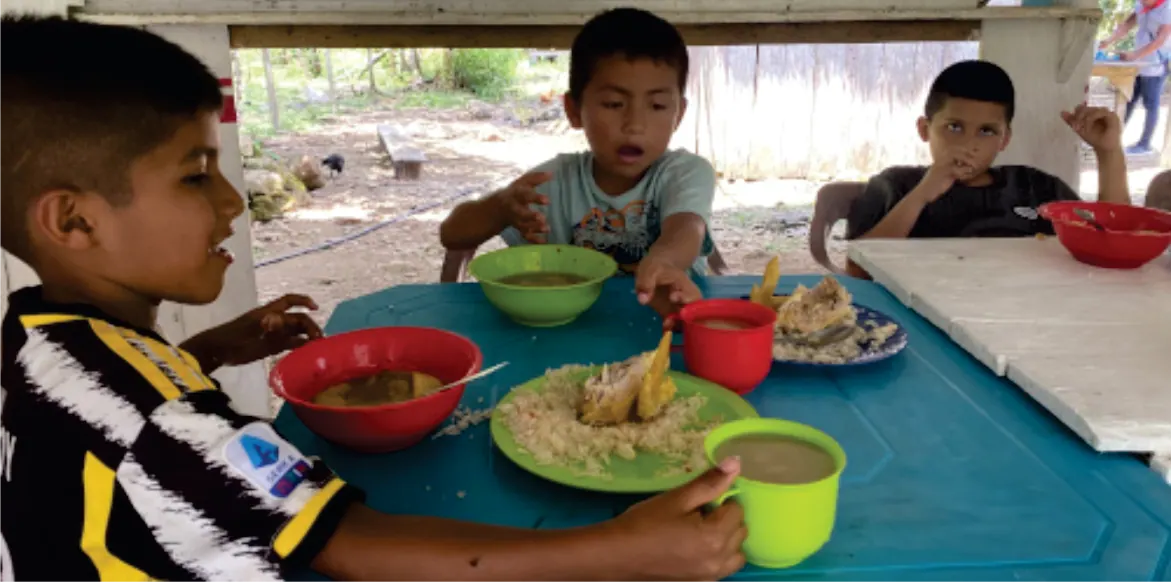 Niños comiendo en una mesa.
