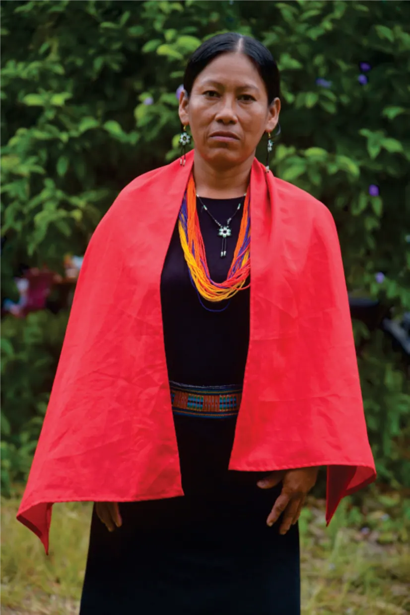 Retrato de una mujer con capa roja y collares en el monte.