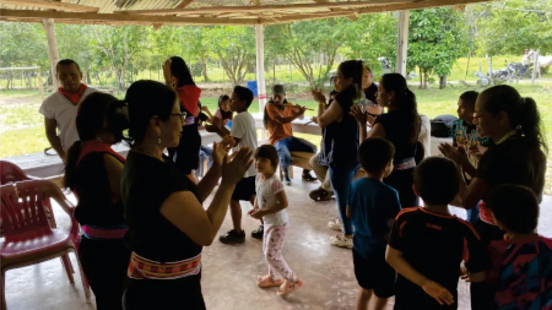 Reunión bajo techo con niños y adultos de pie.
