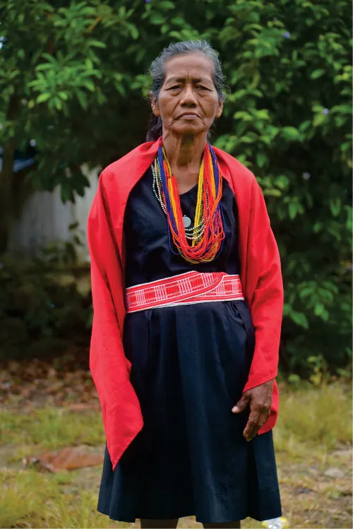Retrato de una mayora con capa roja y faja tejida.