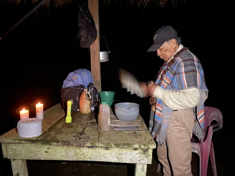 Mayor preparando remedios de noche junto a velas encendidas.